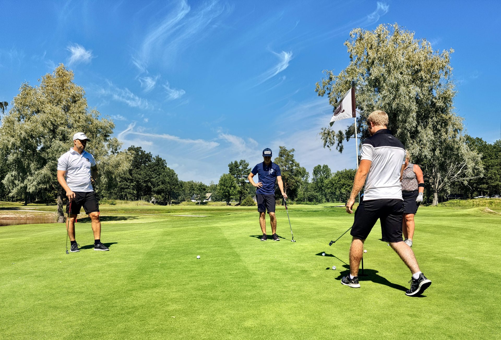 Group of golfers playing on a lush green golf course in Sweden, enjoying a sunny day.